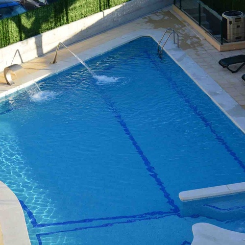 Refreshing Torre Cristina pool with loungers and waterfall. Ideal for relaxation.