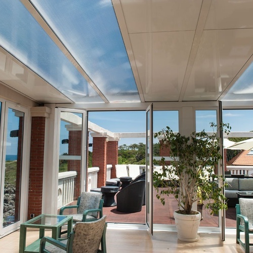 Glazed terrace at Torre Cristina with sea views and outdoor furniture.