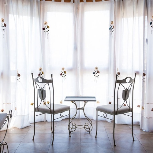 Two chairs and table before embroidered curtains at Torre Cristina.