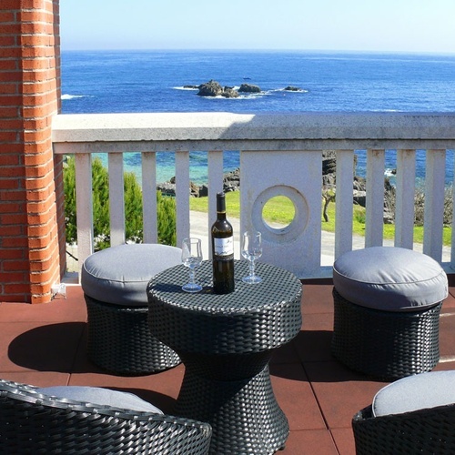 Torre Cristina balcony with sea views, table with wine and stools.
