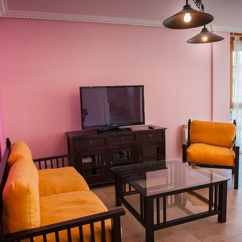 Torre Cristina living room with orange sofa, coffee table, and TV.