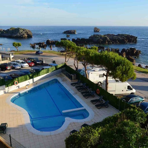 Torre Cristina hotel pool and sea views, with cars and caravans parked.