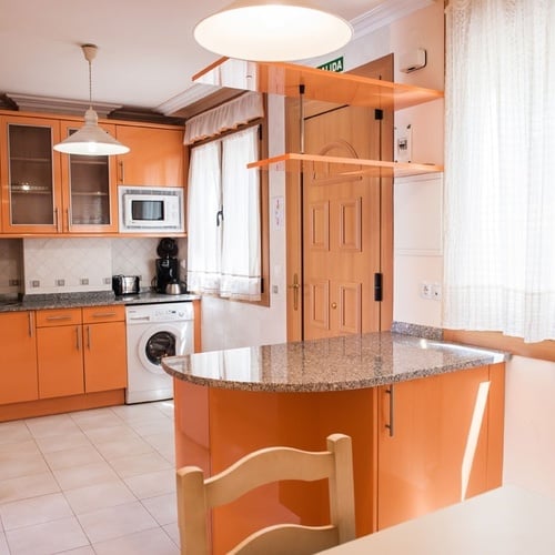 Modern orange kitchen at Torre Cristina with washer and breakfast bar.