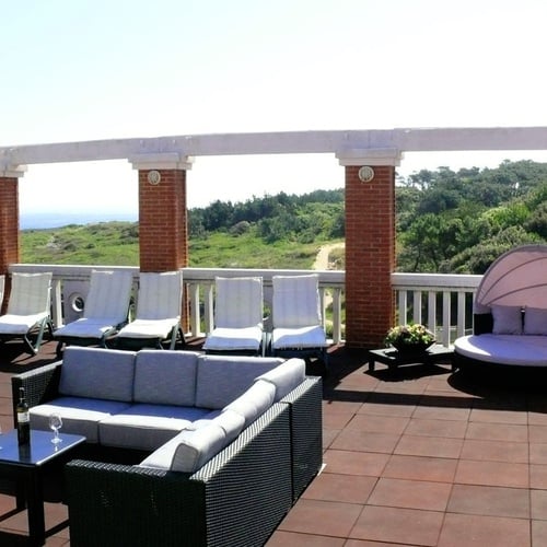 Torre Cristina terrace with sofas, loungers, and ocean views.