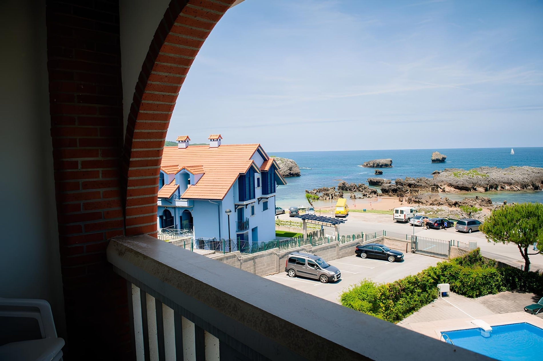 una vista del océano desde un balcón con una casa azul en el fondo