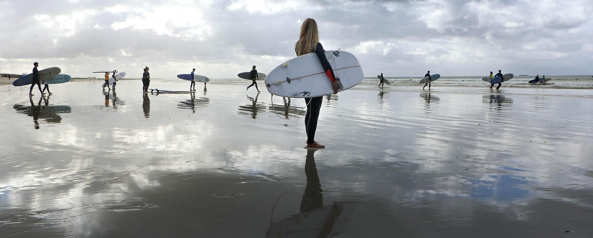 un grupo de surfistas camina por la playa con sus tablas de surf