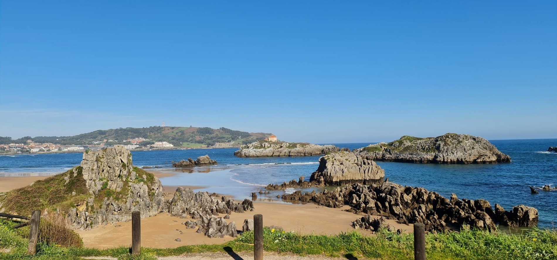 una playa con rocas y un pueblo en la distancia