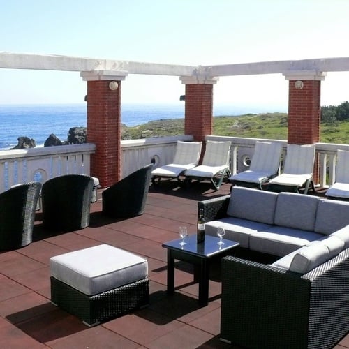 Torre Cristina oceanfront terrace with sofas and lounge chairs.