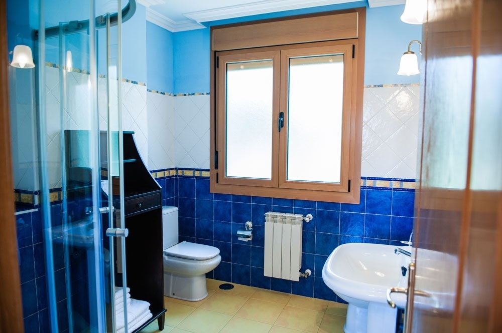a bathroom with blue tiles and a sink and toilet