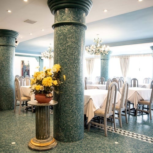 Elegant dining room at Torre Cristina with dressed tables and decorated columns.