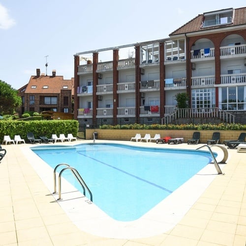 Torre Cristina hotel pool with lounge chairs and building.