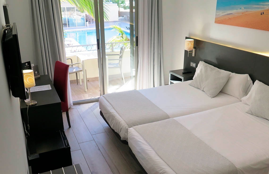 a hotel room with two beds and a sliding glass door