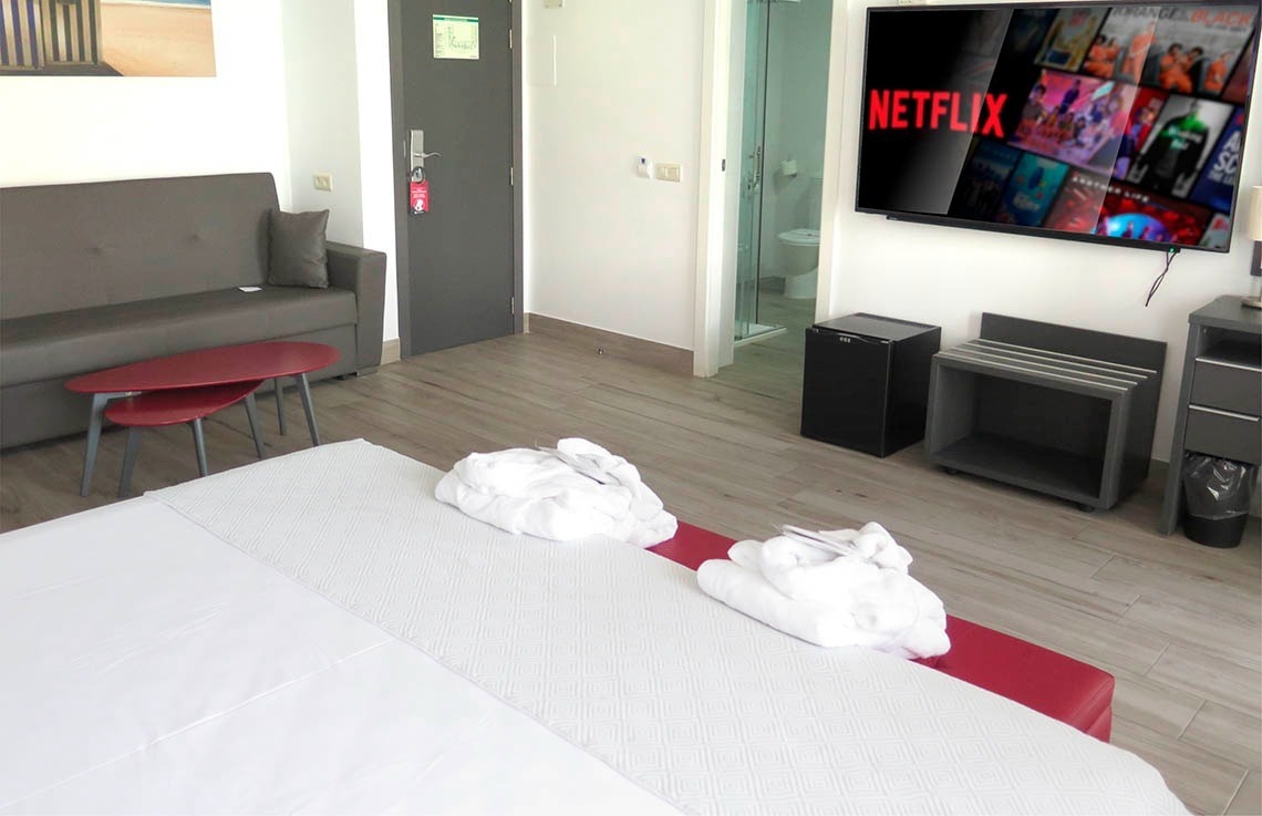 a hotel room with a flat screen tv displaying netflix