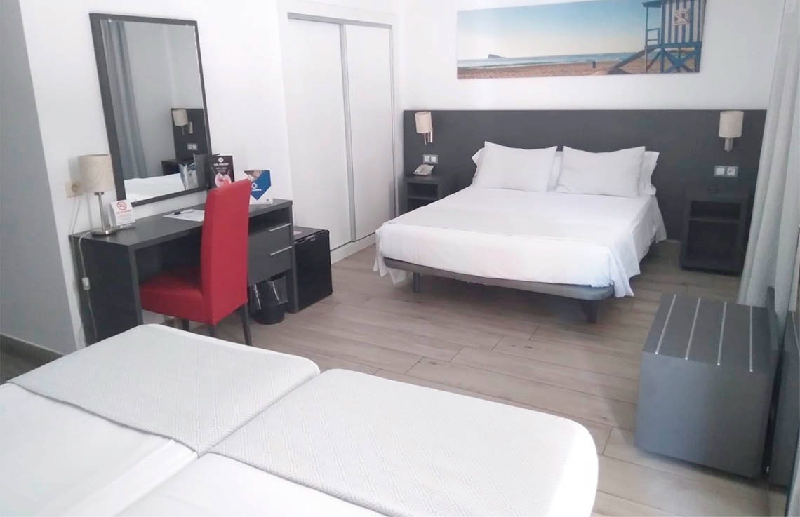 a hotel room with a large bed and a red chair