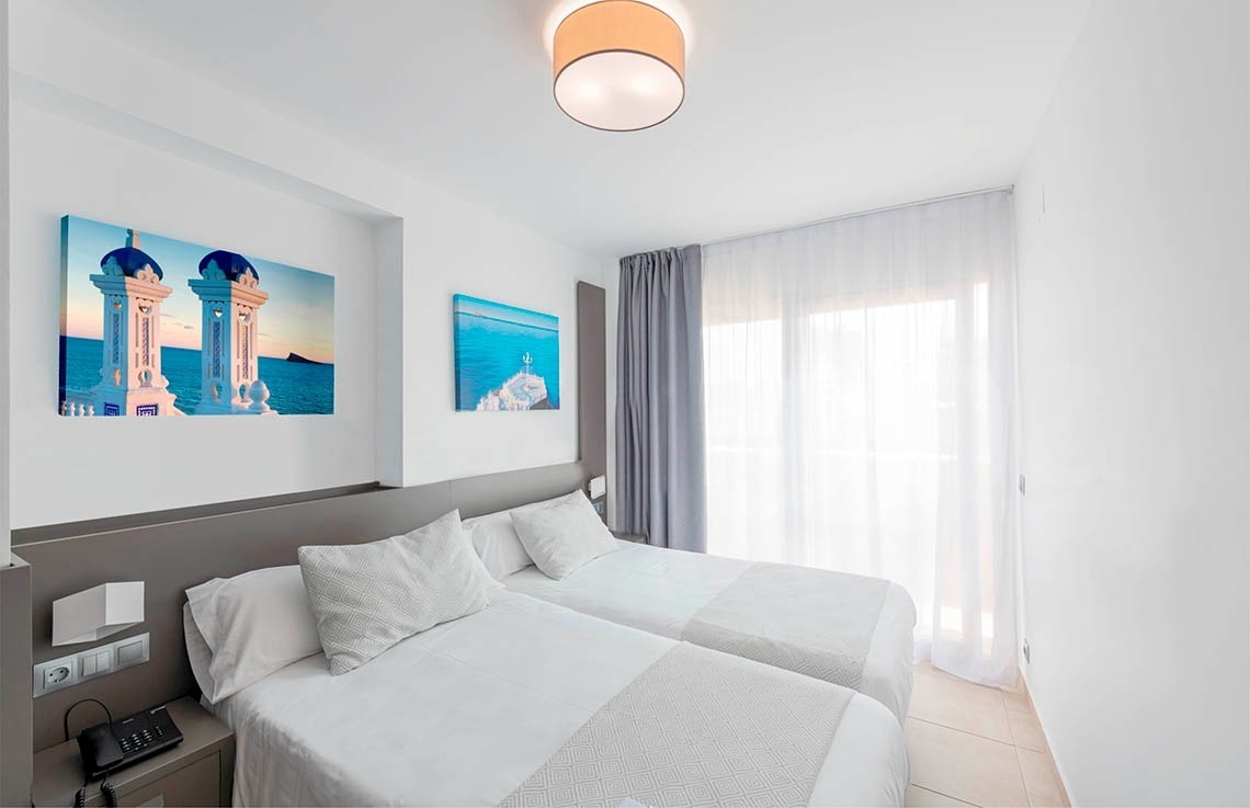 a hotel room with two beds and two paintings on the wall