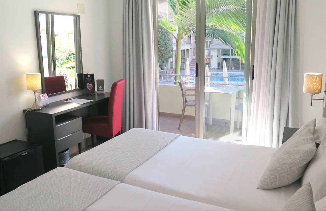 a hotel room with two beds a desk and a mirror