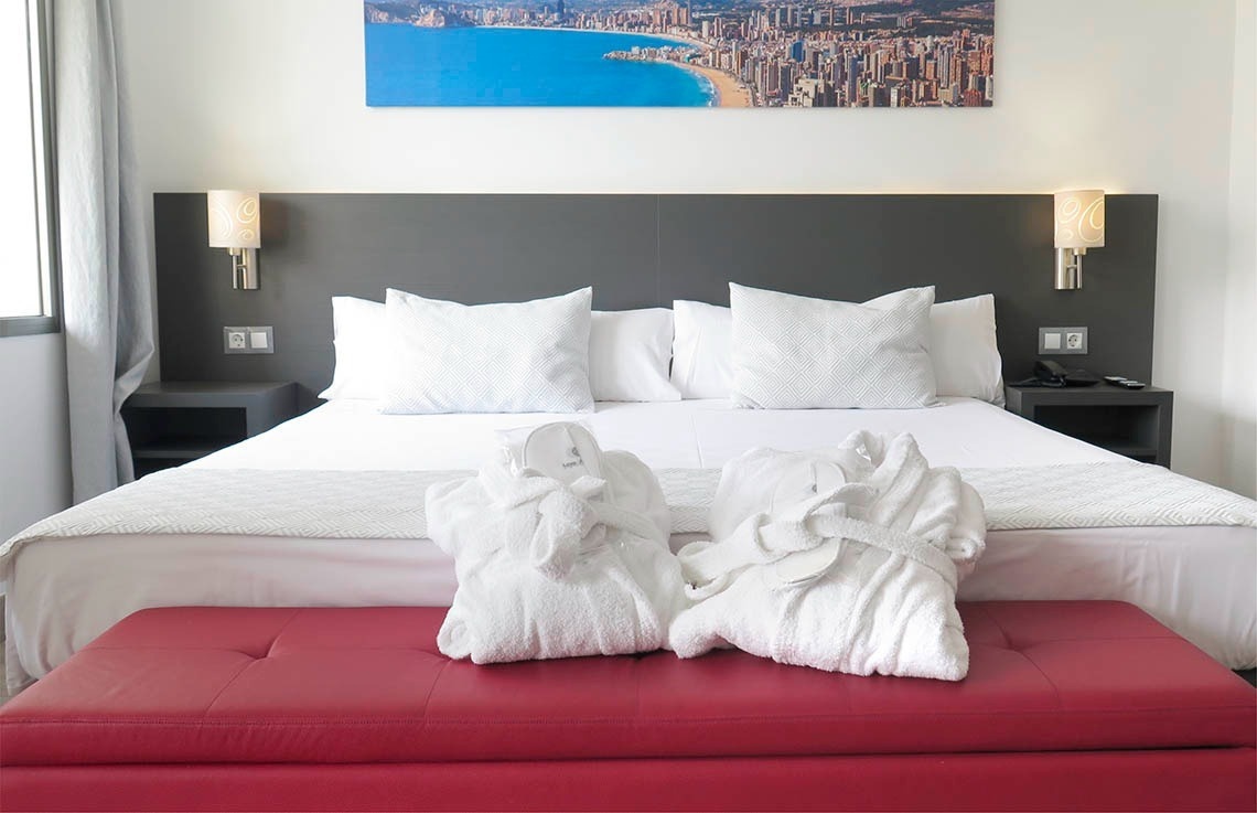 a hotel room with a picture of a beach on the wall above the bed
