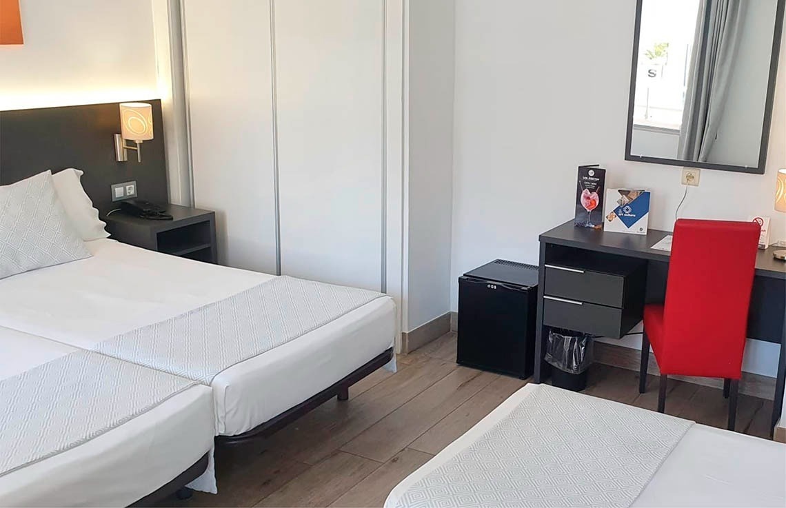 a hotel room with two beds a desk and a mirror