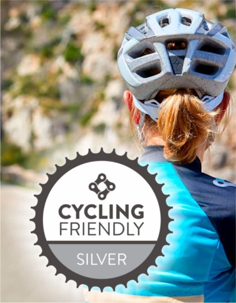una mujer con un casco y una camisa azul está rodeada por un sello de ciclismo amigable de plata