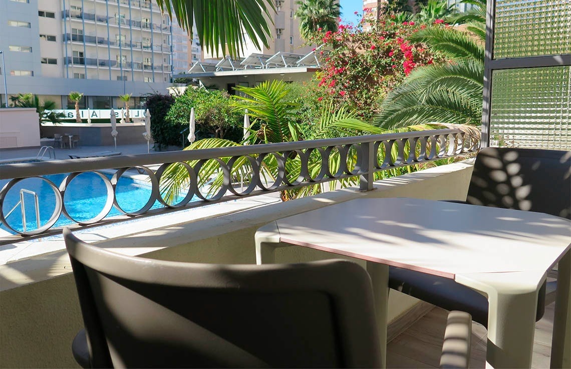 a balcony with a table and chairs overlooking a swimming pool