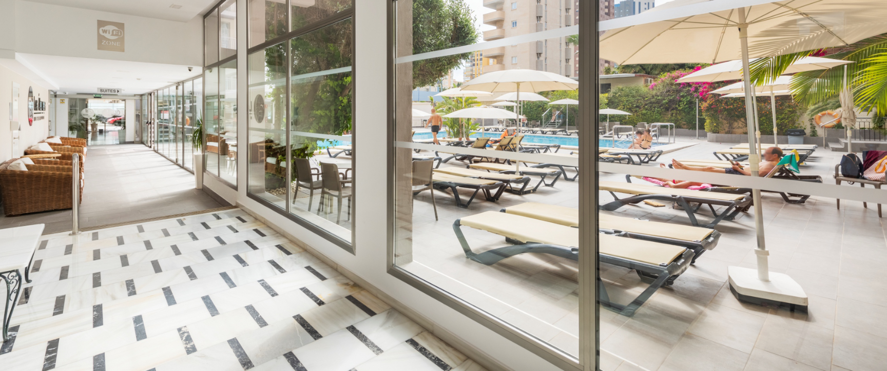 een hotel lobby met stoelen en parasols in de buurt van een zwembad