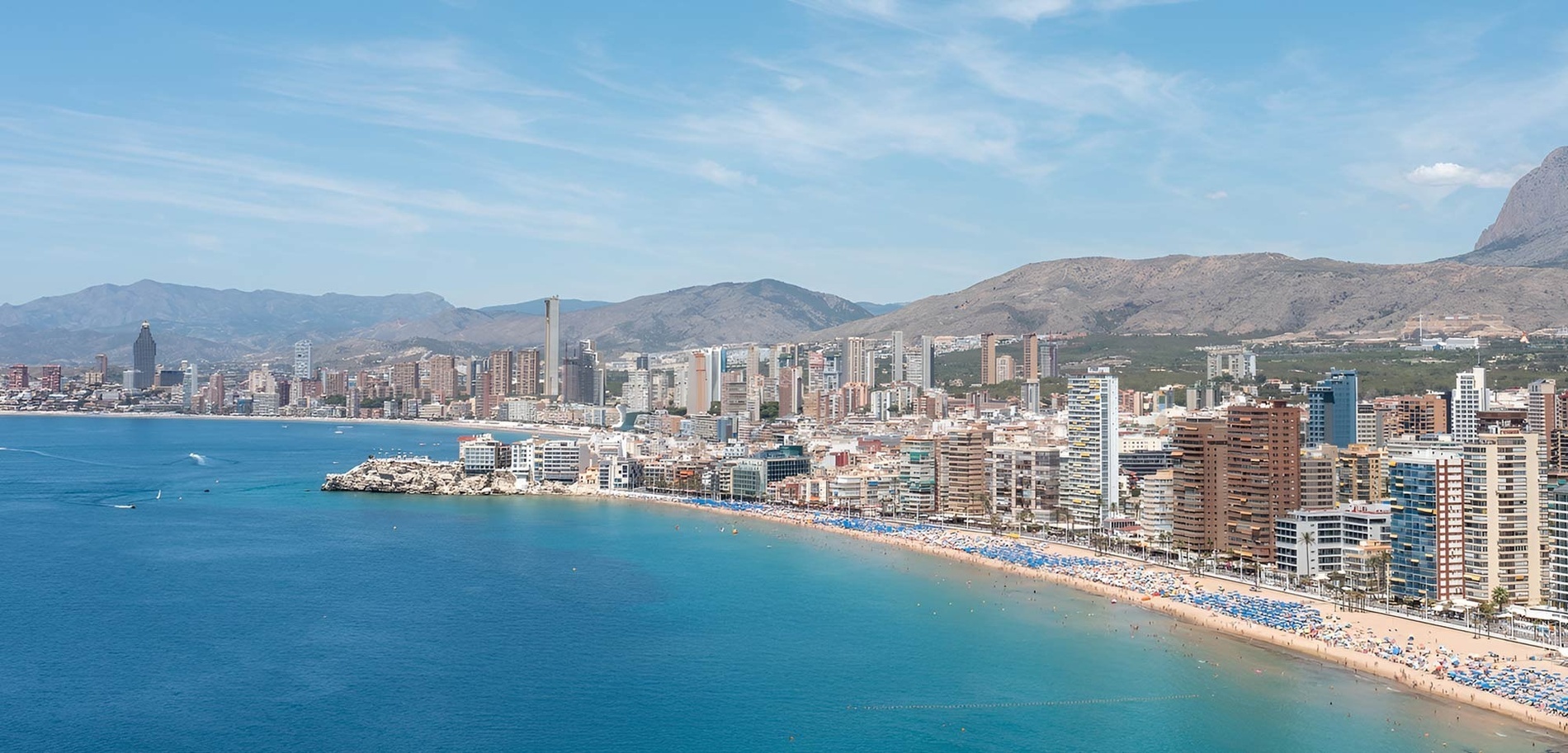 a city with mountains in the background and a beach in the foreground