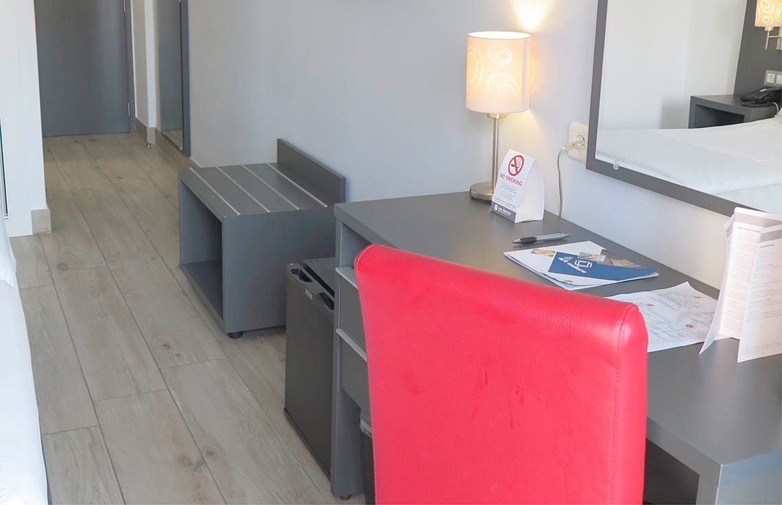 una habitación de hotel con un escritorio y una silla roja