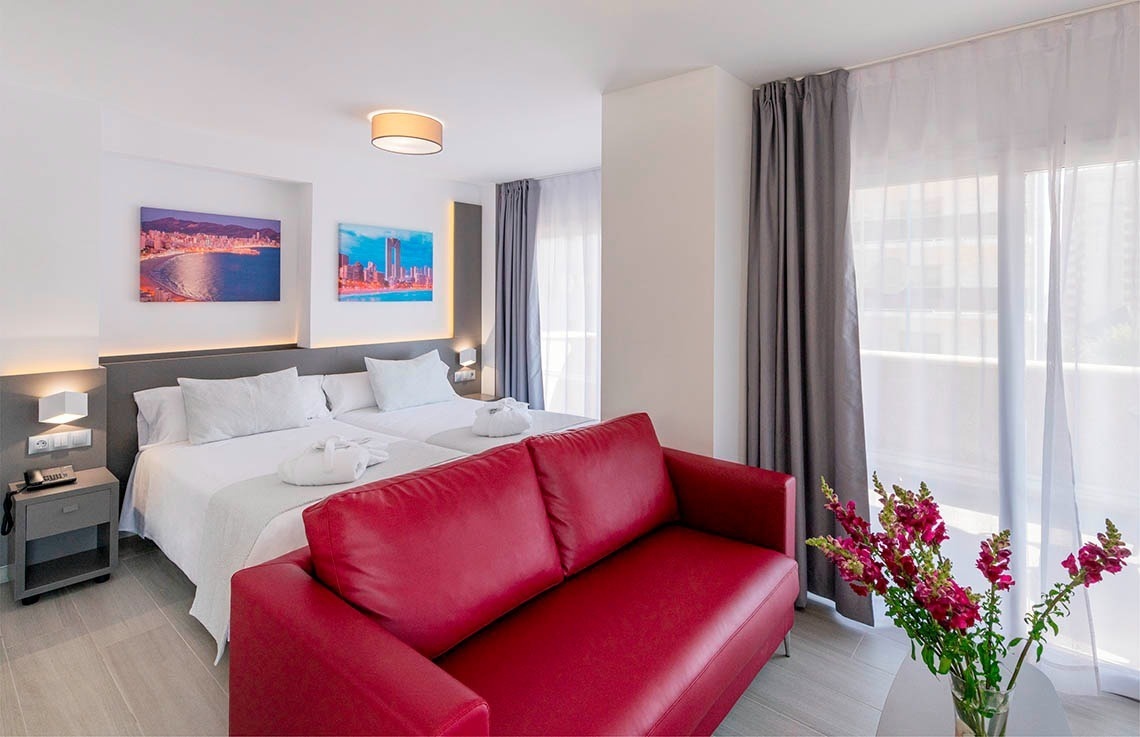 a hotel room with two beds and a red couch
