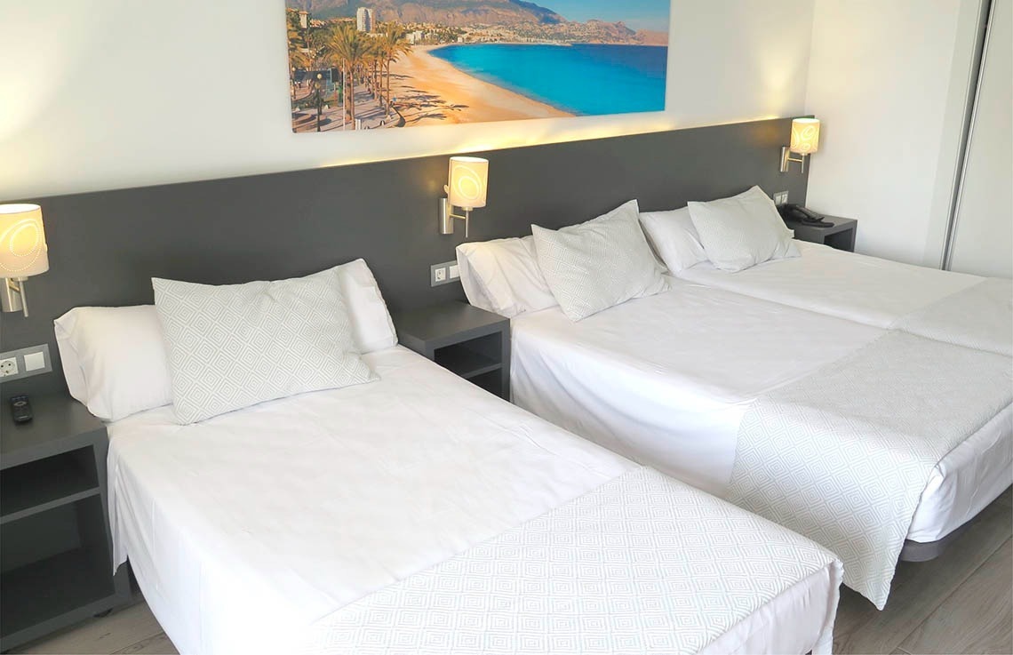 a hotel room with three beds and a picture of a beach on the wall