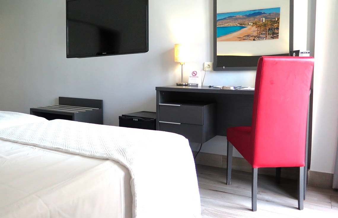 una habitación de hotel con una silla roja y un escritorio