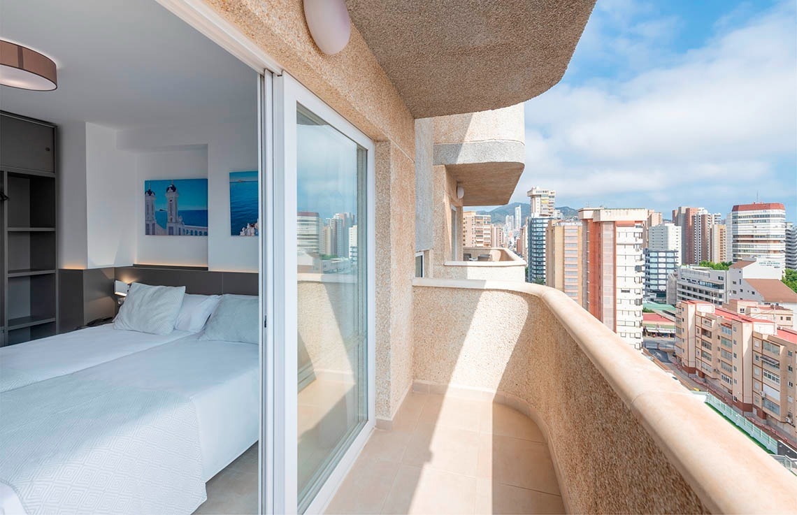 a bedroom with a balcony overlooking a city