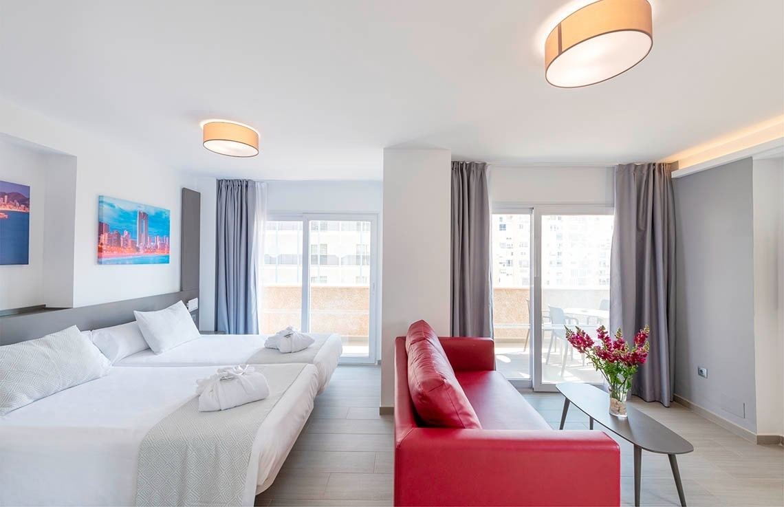 a hotel room with two beds and a red couch