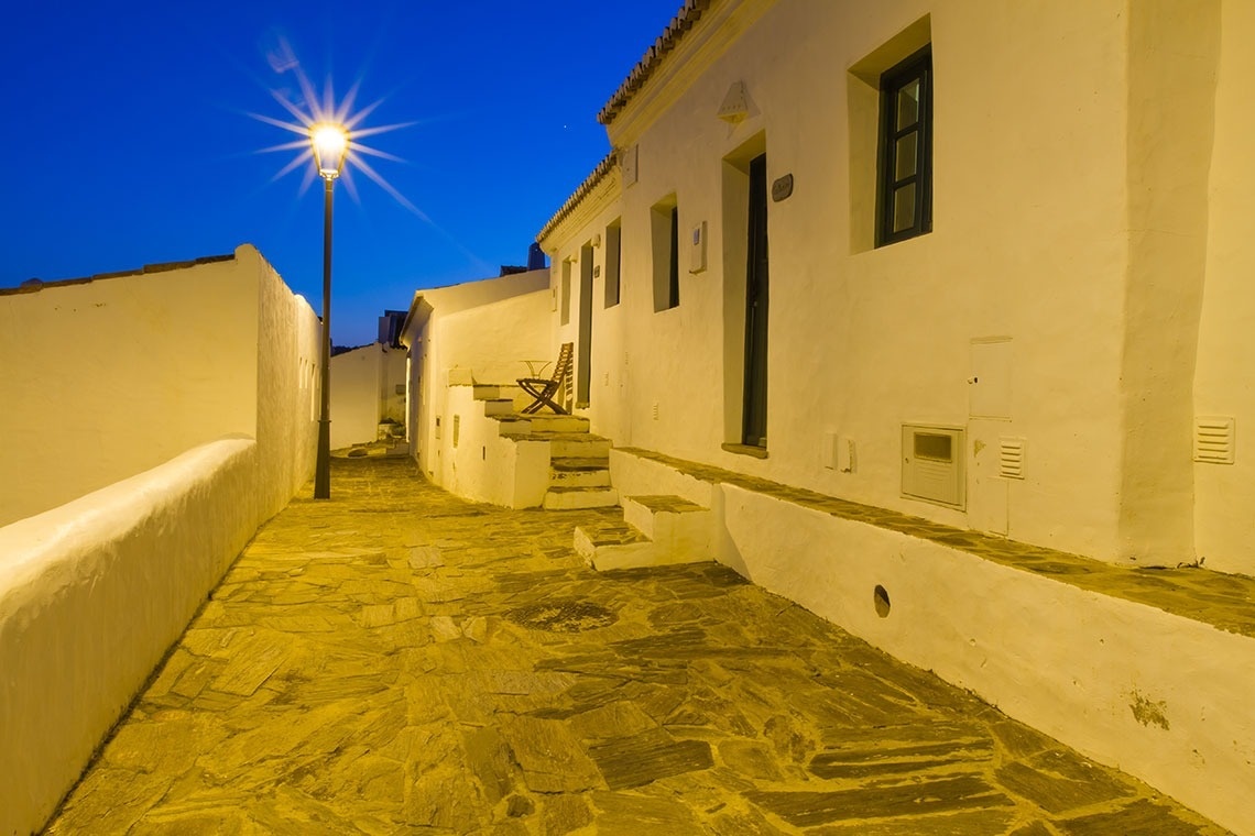 una calle estrecha con edificios blancos al fondo