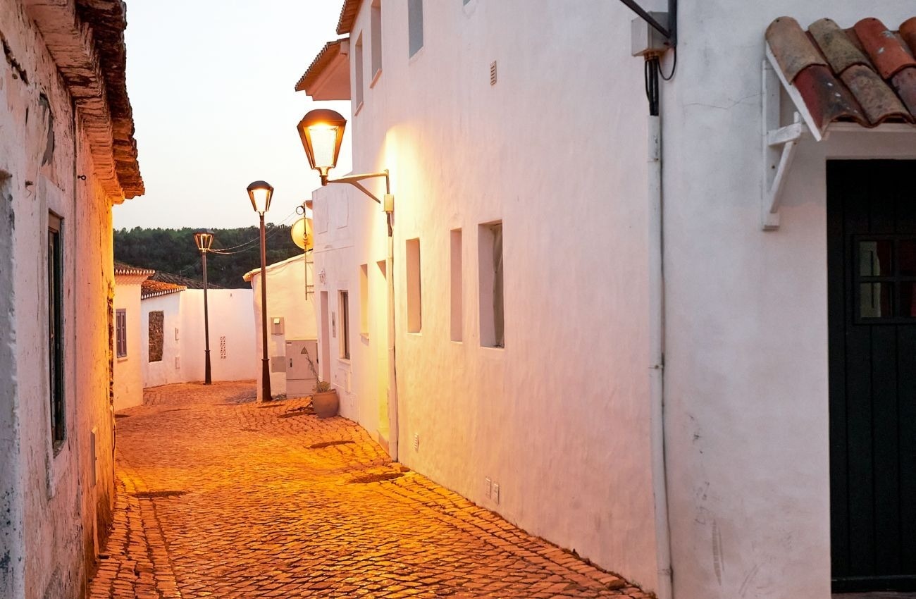 una calle estrecha con edificios blancos y una puerta negra