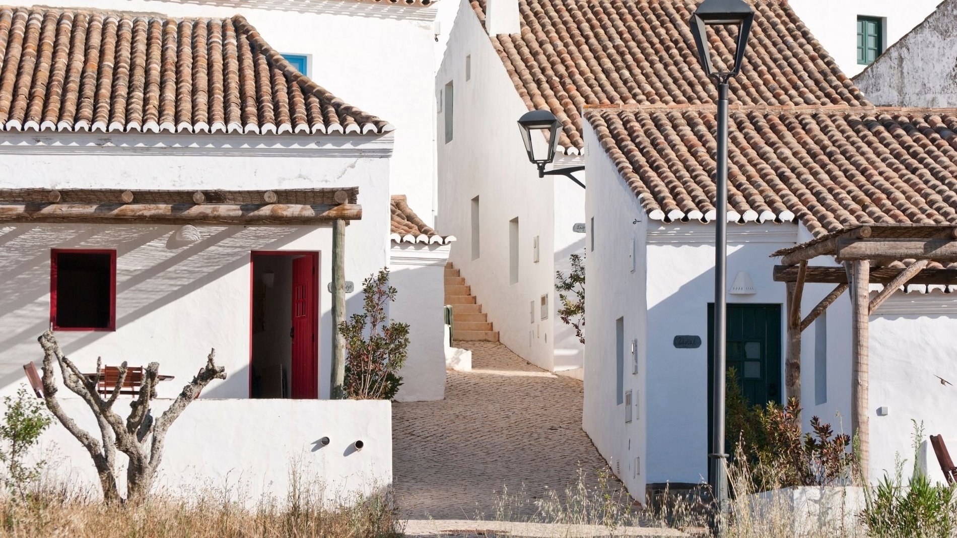 una calle estrecha entre dos casas blancas con techos de tejas rojas