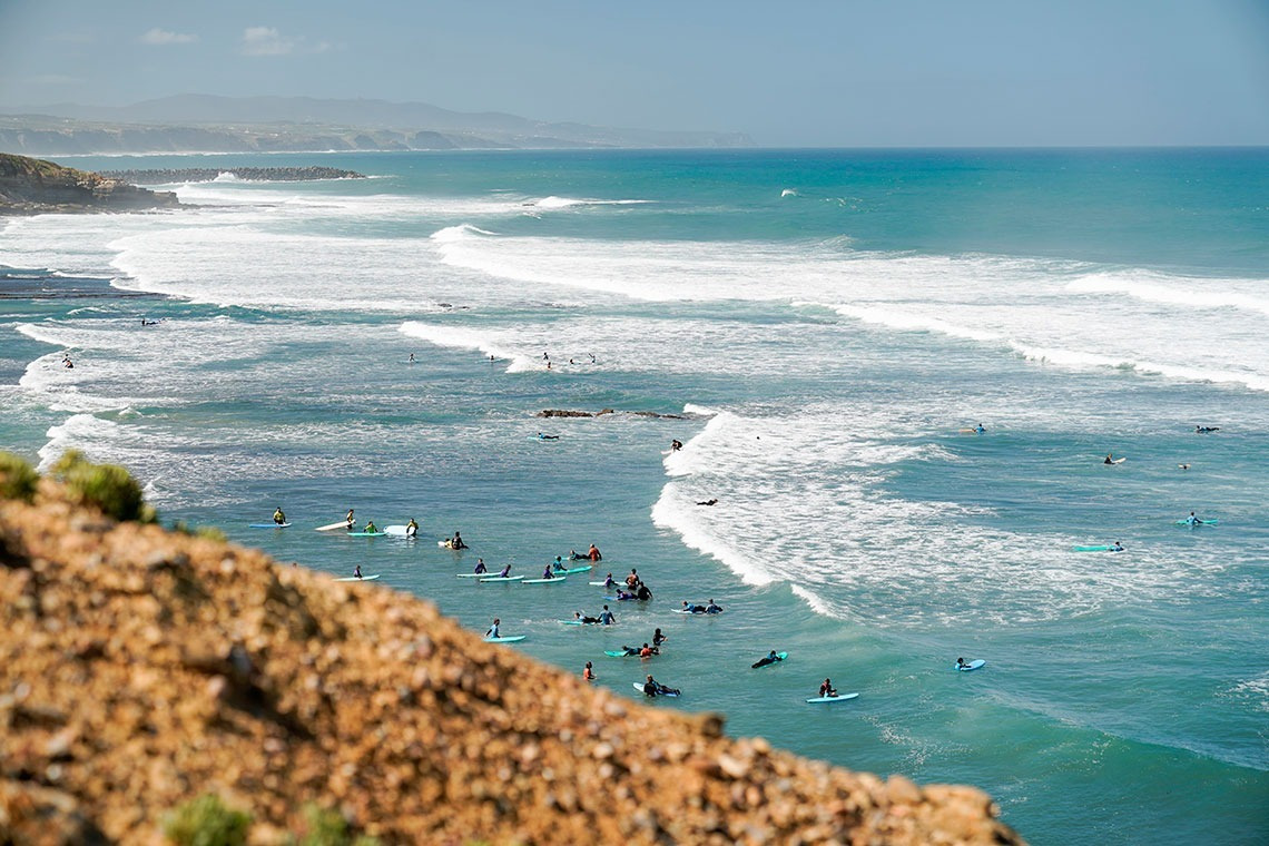 Surfers waiting for waves at a beautiful beach hotel Aldeia da Pedralva.