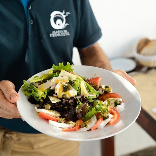 un hombre con una camisa azul sostiene un plato de ensalada