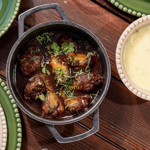 a bowl of mashed potatoes sits next to a pot of stew