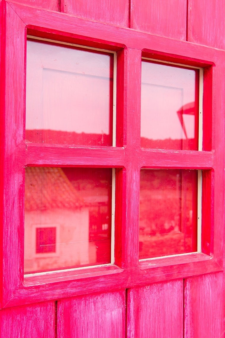 una ventana rosa con un reflejo de una casa en la ventana