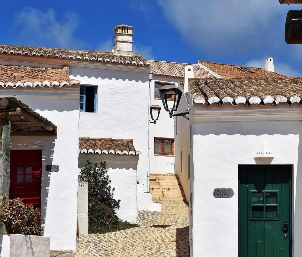 Charming white houses with tiled roofs and colorful doors in Aldeia da Pedralva.