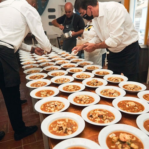 un grupo de hombres están preparando platos de sopa en una mesa