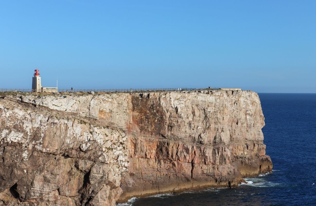 um farol está no topo de um penhasco acima do oceano