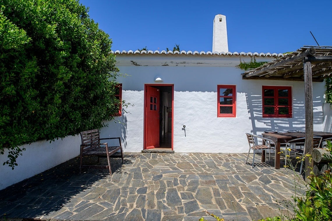 una casa blanca con una puerta roja y ventanas rojas