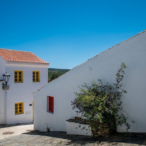 a white building with a red roof and yellow windows