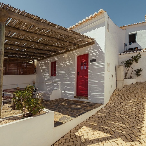 una casa blanca con una puerta roja y un porche de madera