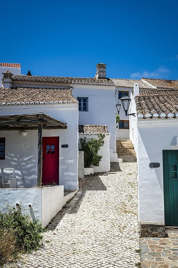 Charming village street with white houses and red Aldeia da Pedralva door.