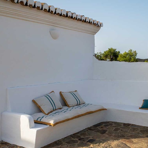 Aldeia da Pedralva's whitewashed patio seating with striped cushions.