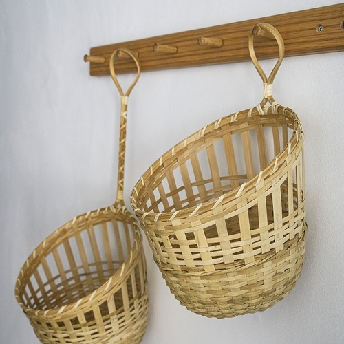 two wicker baskets hanging on a wooden rack