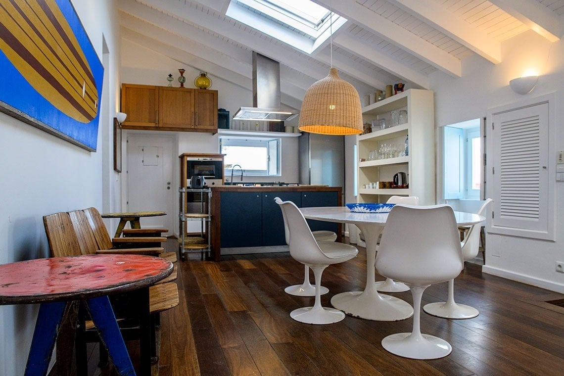 una cocina con una mesa y sillas y una pintura de una tabla de surf en la pared