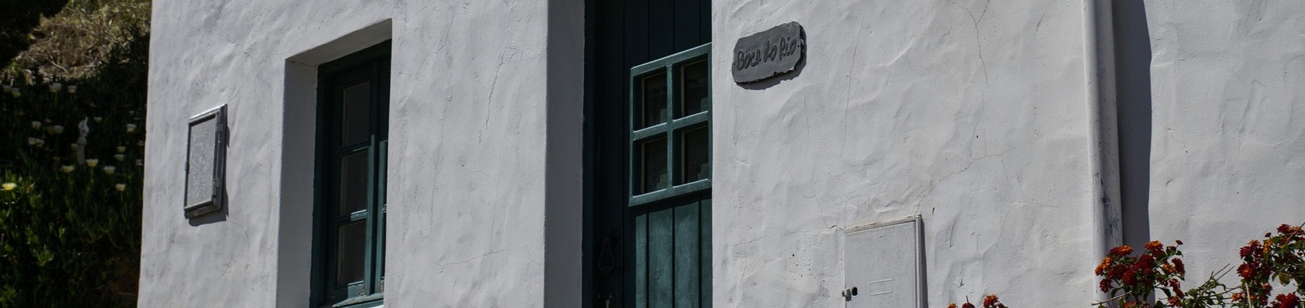 uma casa branca com uma porta verde e uma placa na parede que diz casa